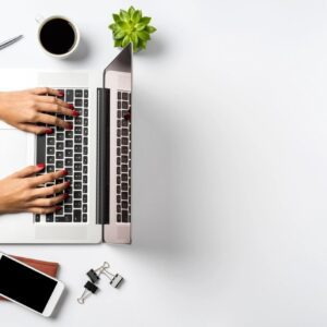 Hands typing on laptop, desk accessories nearby.