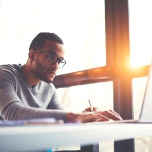Man working on laptop near window.